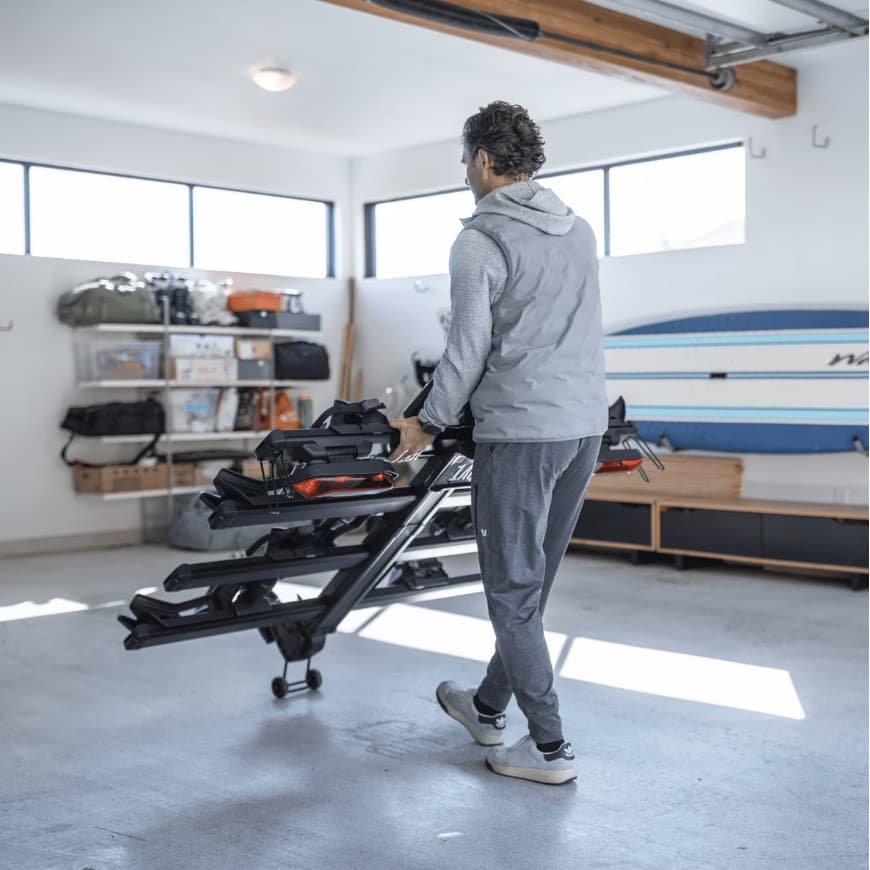 Man walking through garage wheeling the Thule Verse add-on