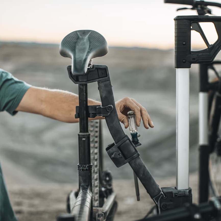 Close up of man repairing bike that is being held up by the Thule Verse Bike Repair holder out in a nature setting